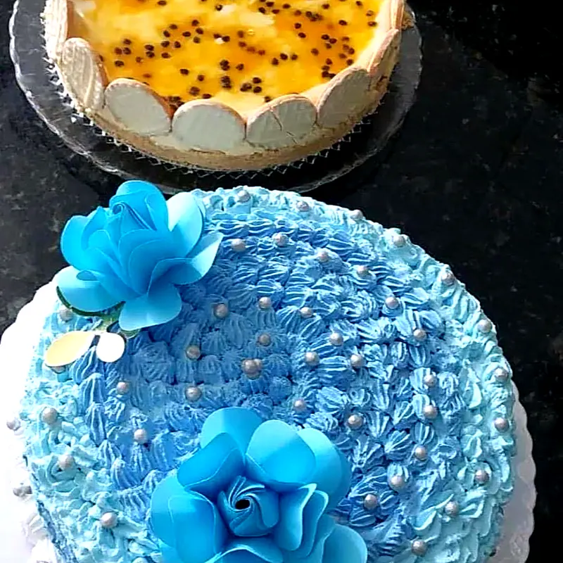 Bolo azul decorado com flores e torta de maracujá